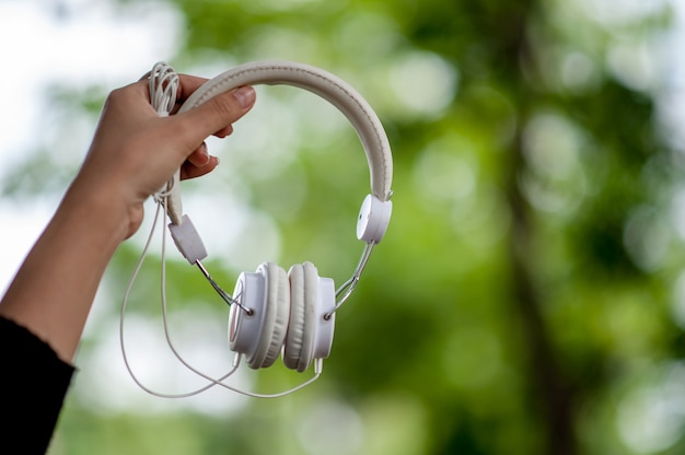 Hand and white headphones, devices for listening to music 
