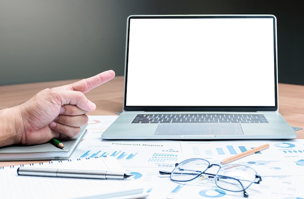 Hand wijzende vinger om de presentatie van de diavoorstelling van de verkoopsamenvatting te bespotten op display-laptop met pen, bril en papierwerk op tafel in vergaderruimte