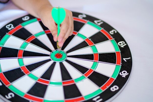 Hand with arrow throw hitting the center of bullseye target or dartboard