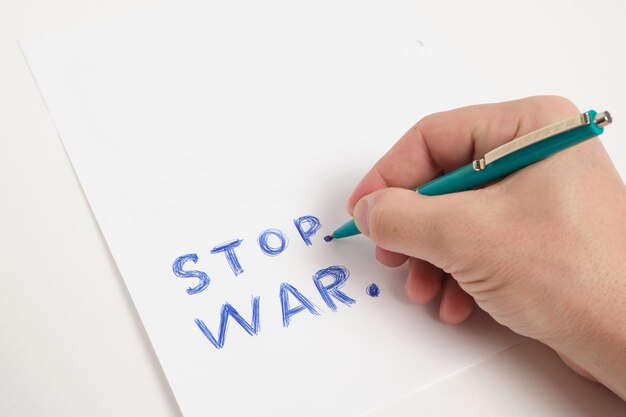 Hand with ballpoint pen and inscription stop war white background