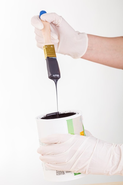 Hand with a brush and a can of paint on a white background