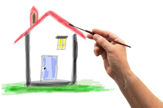 Hand with brush drawing a house on paper