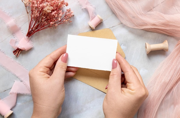 Hand with card and envelope with pink flowers and ribbons