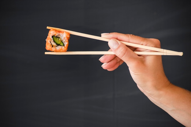 Foto mano con le bacchette e il rotolo di sushi