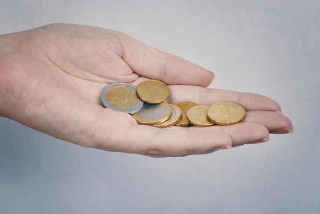 Hand with coins on grey background womans hand with metal coins concept of financial savings donatio...