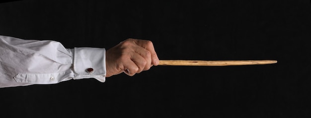 Hand with conductor baton on black background