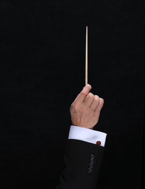 Hand with conductor baton on black background