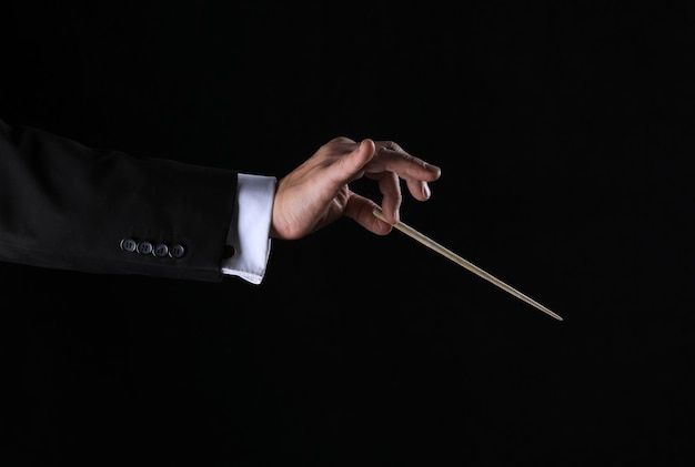 Hand with conductor baton on black background