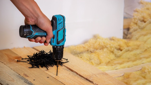 Hand with cordless screwdriver and drill isolated on white background. Twists screws into the board.