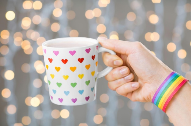 hand with cup of cacao and gay awareness wristband