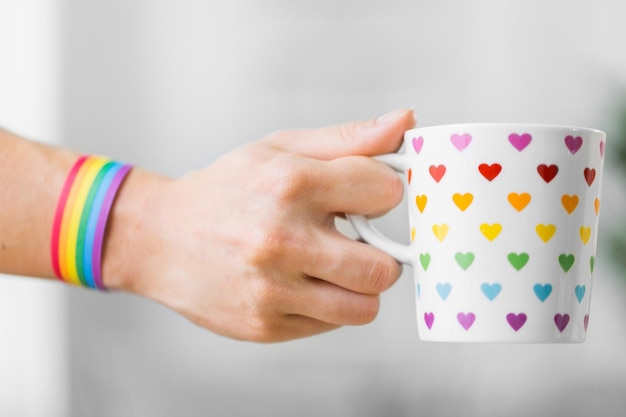 Photo hand with cup of cacao and gay awareness wristband