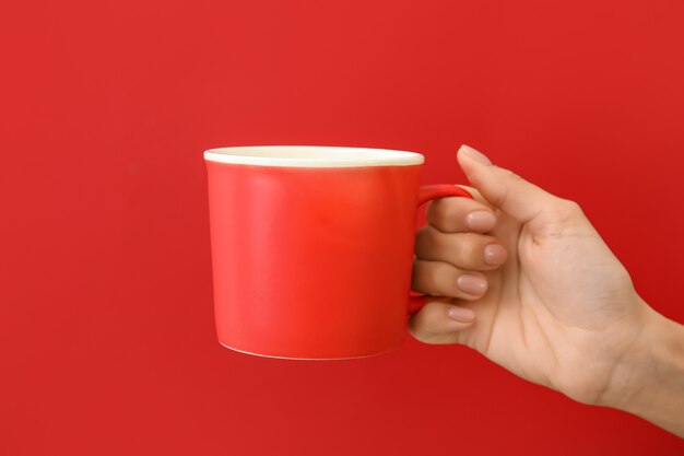 Hand with cup on color surface