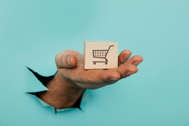 Photo hand with a delivery box through a blue paper hole