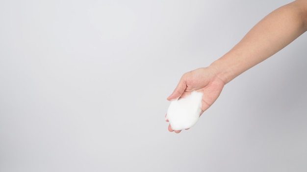 Mano con sapone per le mani schiumogeno per il lavaggio su sfondo bianco.