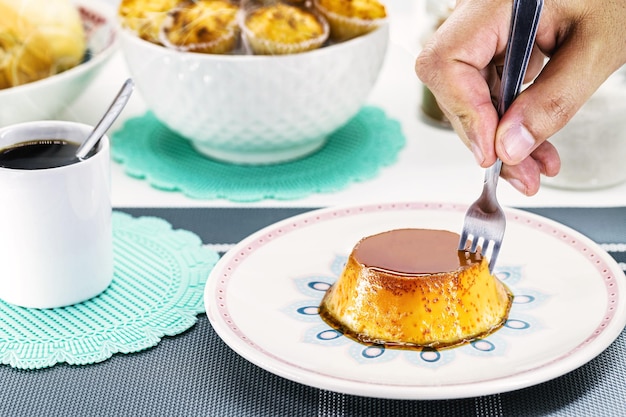 Hand with fork serving sweet condensed milk pudding typical Brazilian dessert