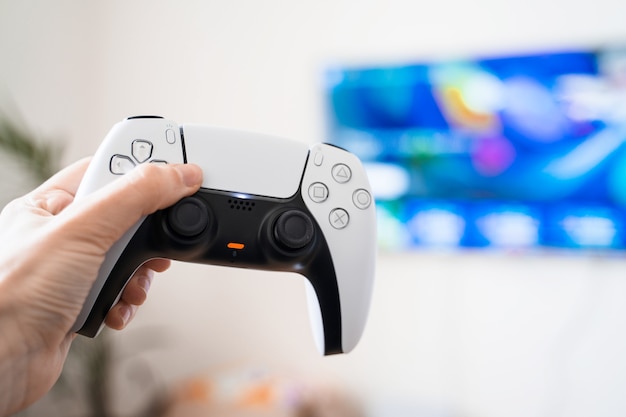 Photo hand with gamepad and tv set with blurred game.