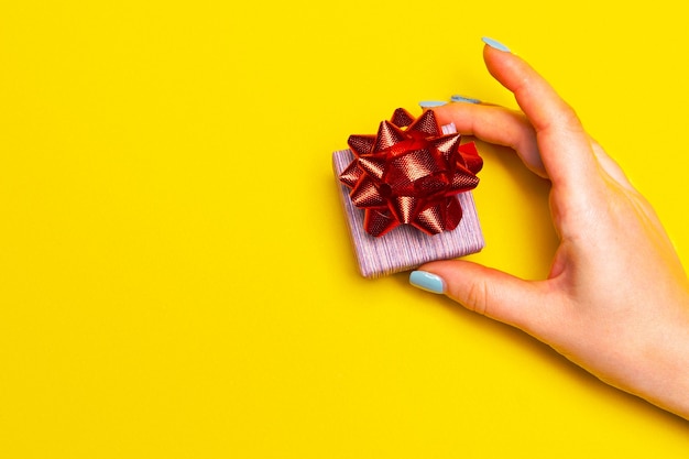 Hand with a gift box on yellow background boxing day ideas space for text