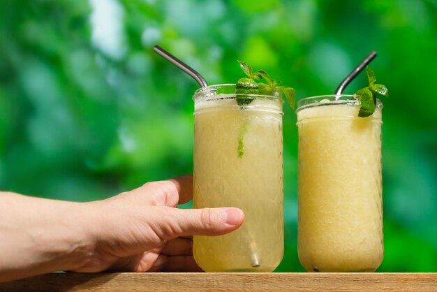 Hand with glass of melon smoothie on table bar outdoors