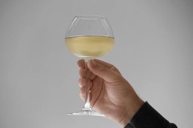 Photo hand with glass of white wine on grey background