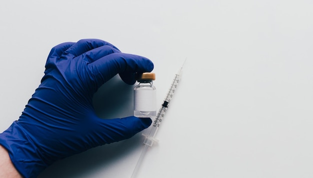 흰색 배경 및 복사 공간 위에 주사기와 유리병에 백신을 보여주는 장갑과 손