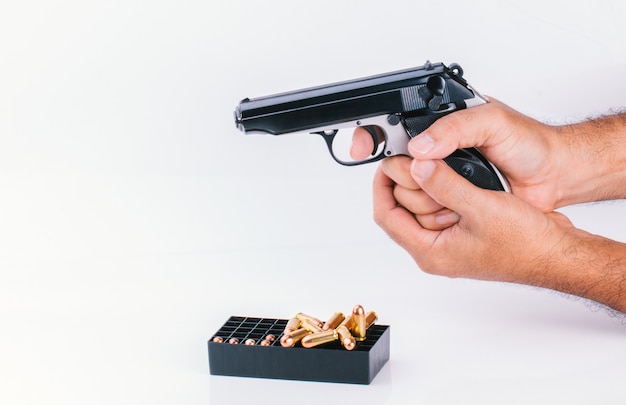 Hand with gun isolated on white wall