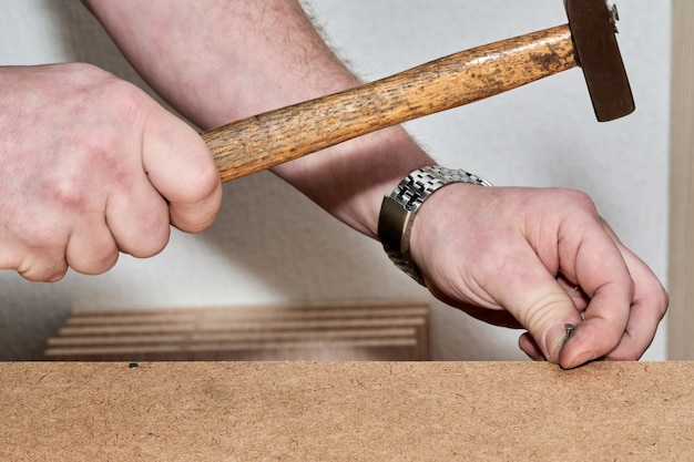 Hand with hammer hammer hammers nail when assembling furniture