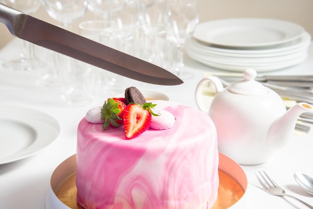 Foto mano con un coltello per tagliare la torta sulla torta di compleanno della festa deliziosa torta fondente rosa biscotto
