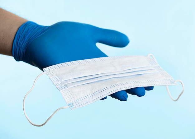 Hand with latex glove holding medical mask