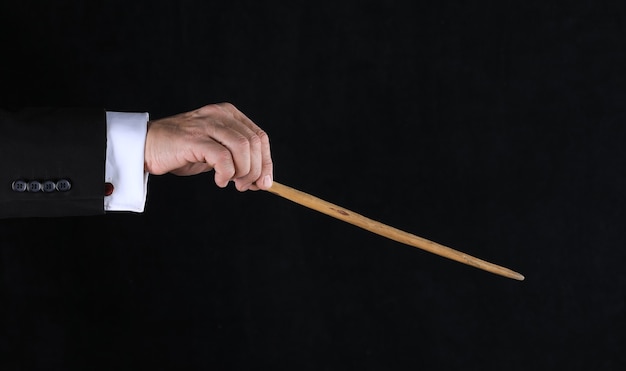 Hand with magic wand on black background