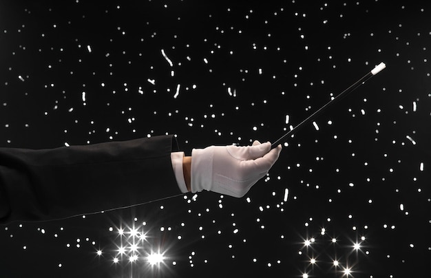 hand with a magic wand on a black starry background