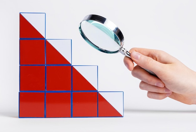 Foto mano con lente d'ingrandimento sul grafico che cade dai cubi analisi delle ragioni e delle conseguenze del fallimento aziendale e della crisi economica ricerca e pianificazione di modi per risolvere i problemi