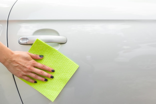 Hand with microfiber cloth cleaning car