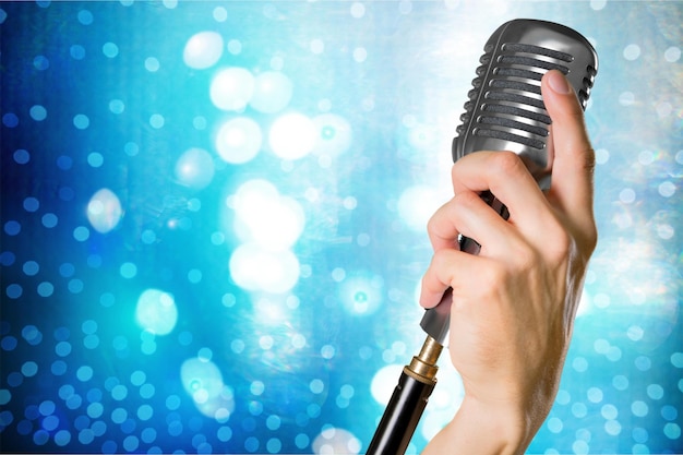 Hand with microphone on blue background