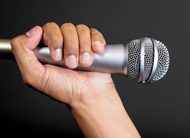 hand with microphone on gray background close up AI Generated