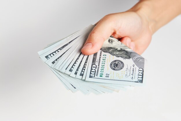 Hand with money isolated on white background with copy space. Woman hand giving dollar money, close-up