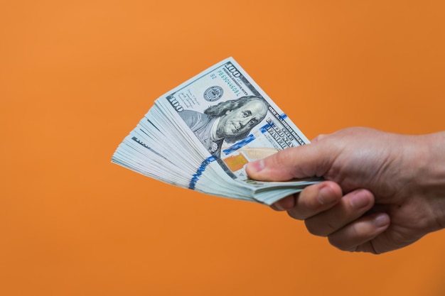 Hand with money on orange background American dollars Money or Business concept