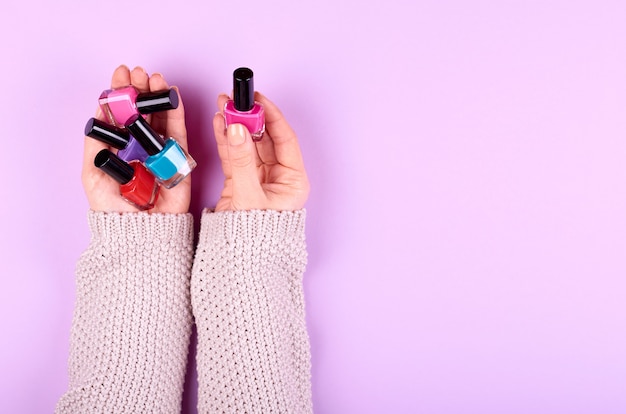 Hand with nail polish bottles.