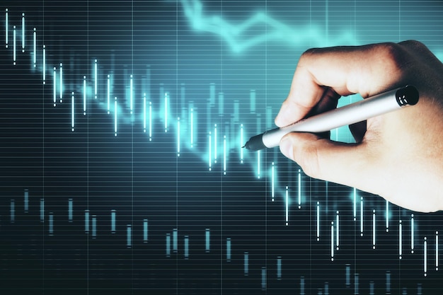 Hand with pen drawing stock market crash chart