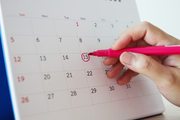 Hand with pen mark at 15th on calendar date