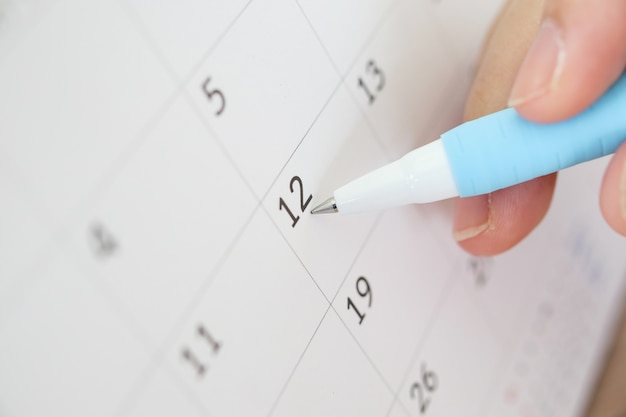 Hand with pen writing on calendar date