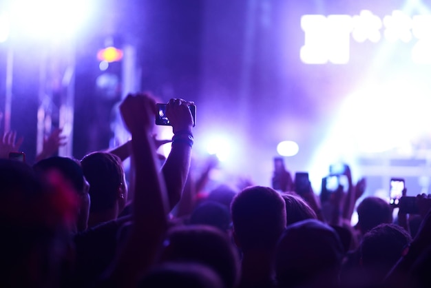 Hand with phone records live music festival People taking photograph with smart phone during concert