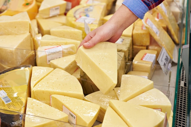 Hand with a piece of cheese in supermarket