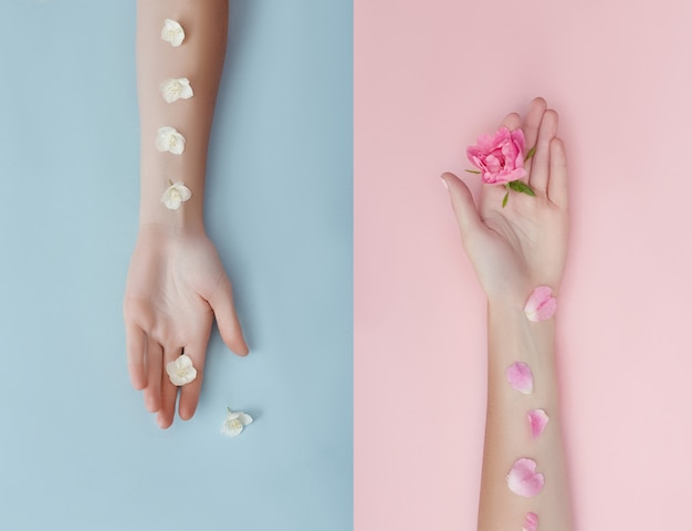 Hand with pink flowers and petals lying on a paper background