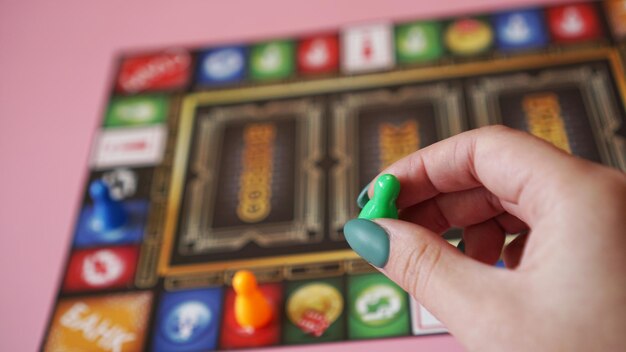 Foto mano con chip di plastica sullo sfondo di giochi da tavolo sfocati colorati, momenti di gioco