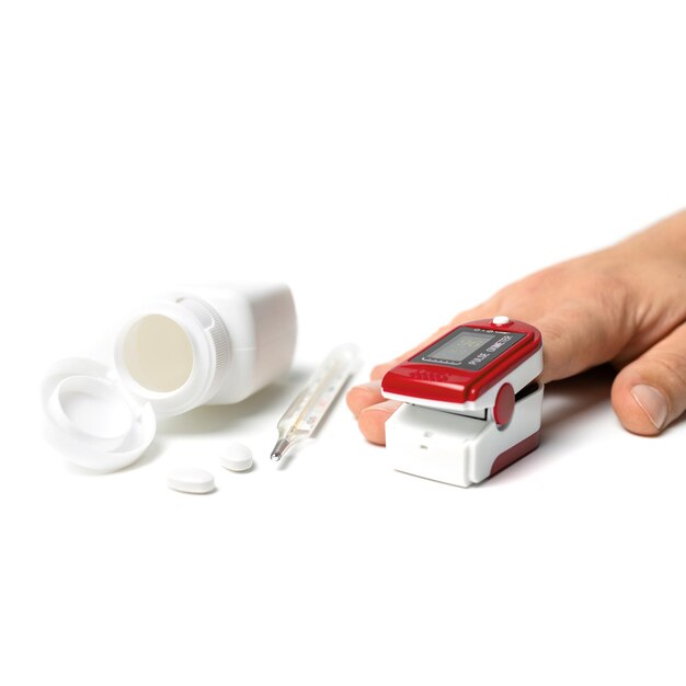 Hand with a portable pulse oximeter on a finger, thermometer and pills isolated on a white background