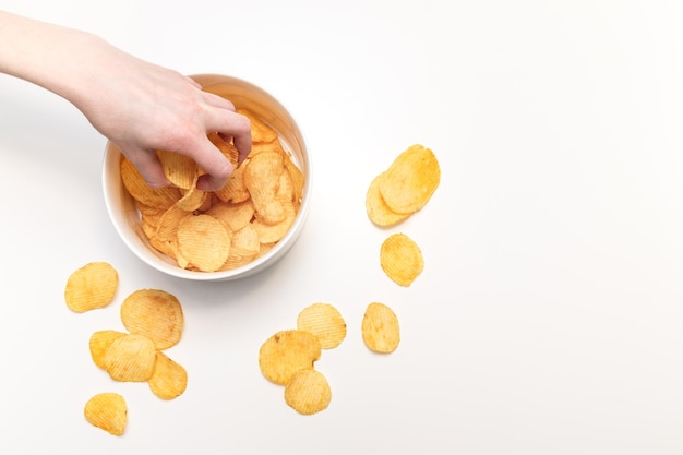 Hand with potato chips and bowl on white background