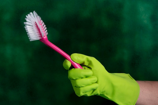 Hand with protective glove holding packaging of cleaning products used for home hygiene