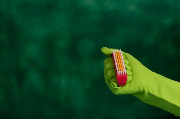 Hand with protective glove holding packaging of cleaning products used for home hygiene