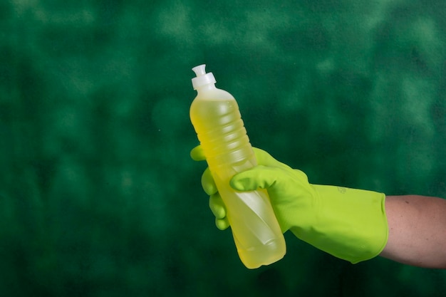 Hand with protective glove holding packaging of cleaning products used for home hygiene