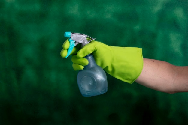 Hand with protective glove holding packaging of cleaning products used for home hygiene